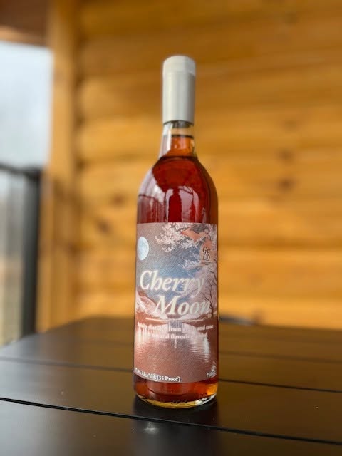 Bottle of Cherry Moon moonshine on a patio table